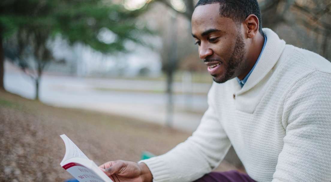 Man reading book at a park.